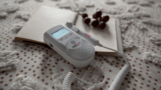  Mini fetal doppler on a bed next to headphones