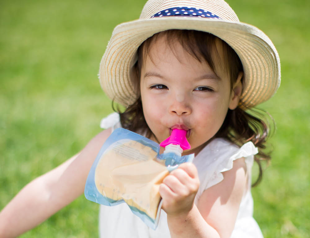 Lifestyle shot of a toddler enjoying her food or drink from the On the go food pouch