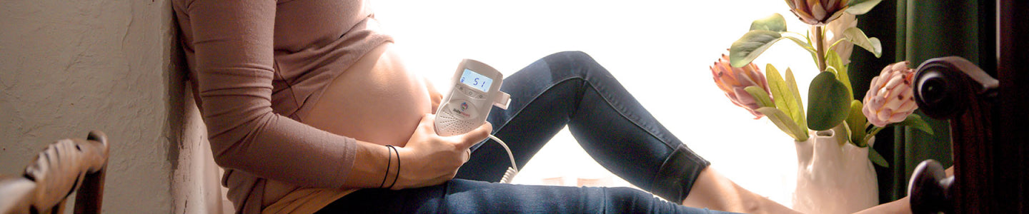 pregnant woman sitting at home holding the Babyheart advanced fetal doppler