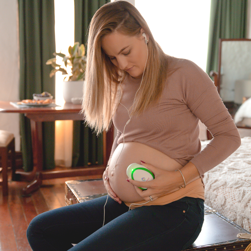 Mother to be using the mini fetal doppler listening to the heartbeat of her unborn baby