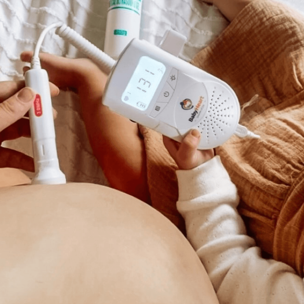 Pregnant mom using the Babyheart Standard doppler while her toddler listens to the baby's heartbeat. baby's heart rate 131 is displayed on the screen