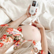 Pregnant woman sitting in bed using the BabyHeart Premium doppler with the baby's heart rate 135 on the screen