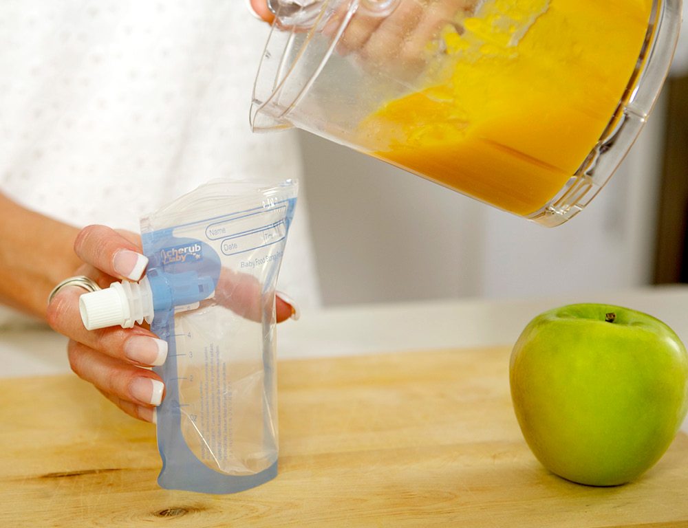 Close up shot of a person pouring in a homemade smoothie or blended carrots into the on the go food pouch