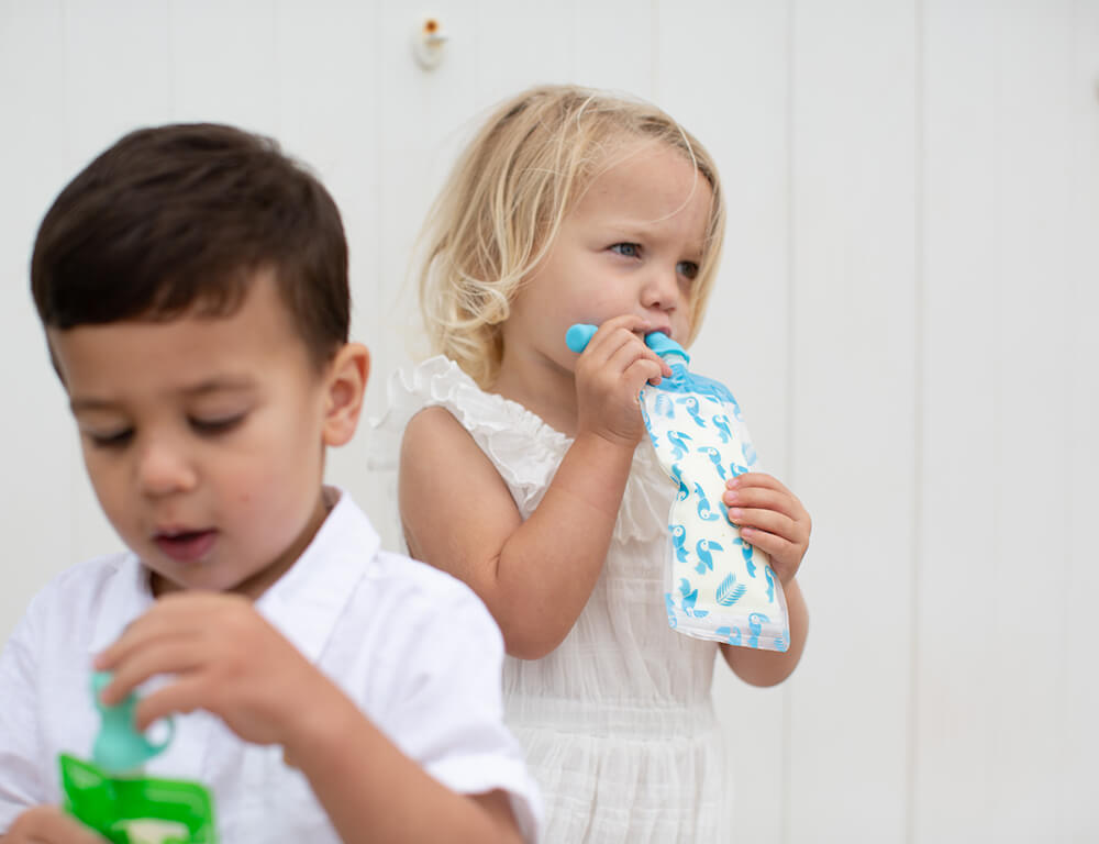 Lifestyle image of 2 toddlers. One is drinking from the Cherub Baby Maxi food pouch in blue