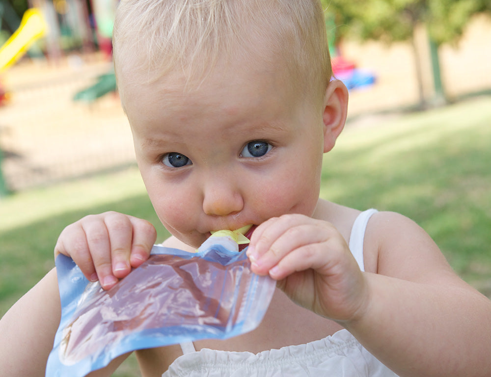 Lifestyle shot of a young toddler enjoying food or from the On the go food pouch