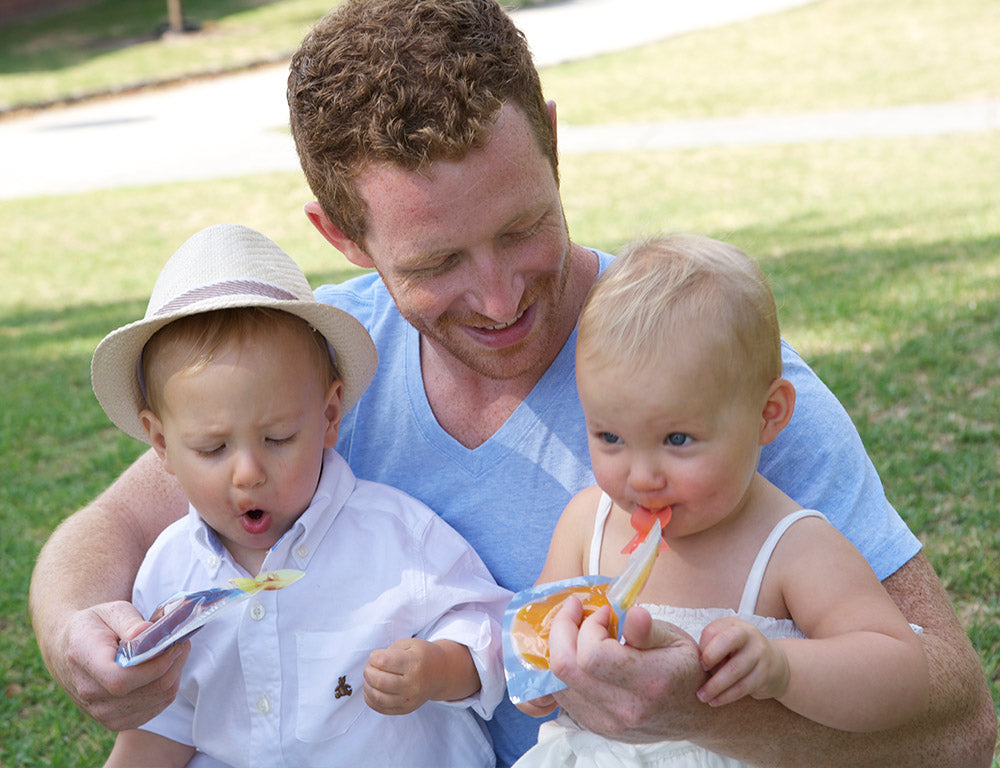 Lifestyle shot of dad and 2 toddlers having a meal from the on the go food pouches